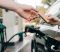 Cropped view of woman giving credit card to worker of gas station while fueling auto